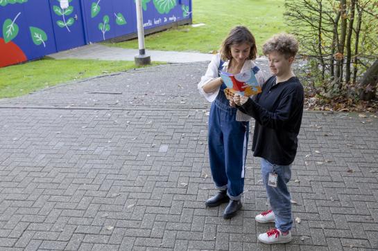 Twee vrouwen kijken in een brochure op een groene campus